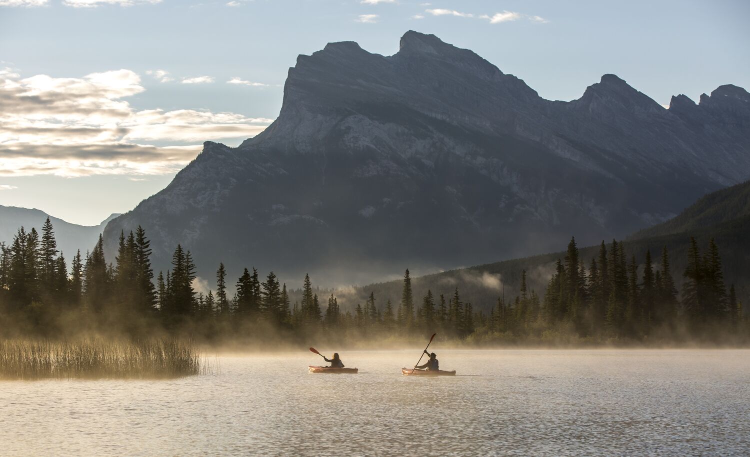 Two kayaks paddle on Vermilion Lakes at sunrise in Banff, Canada