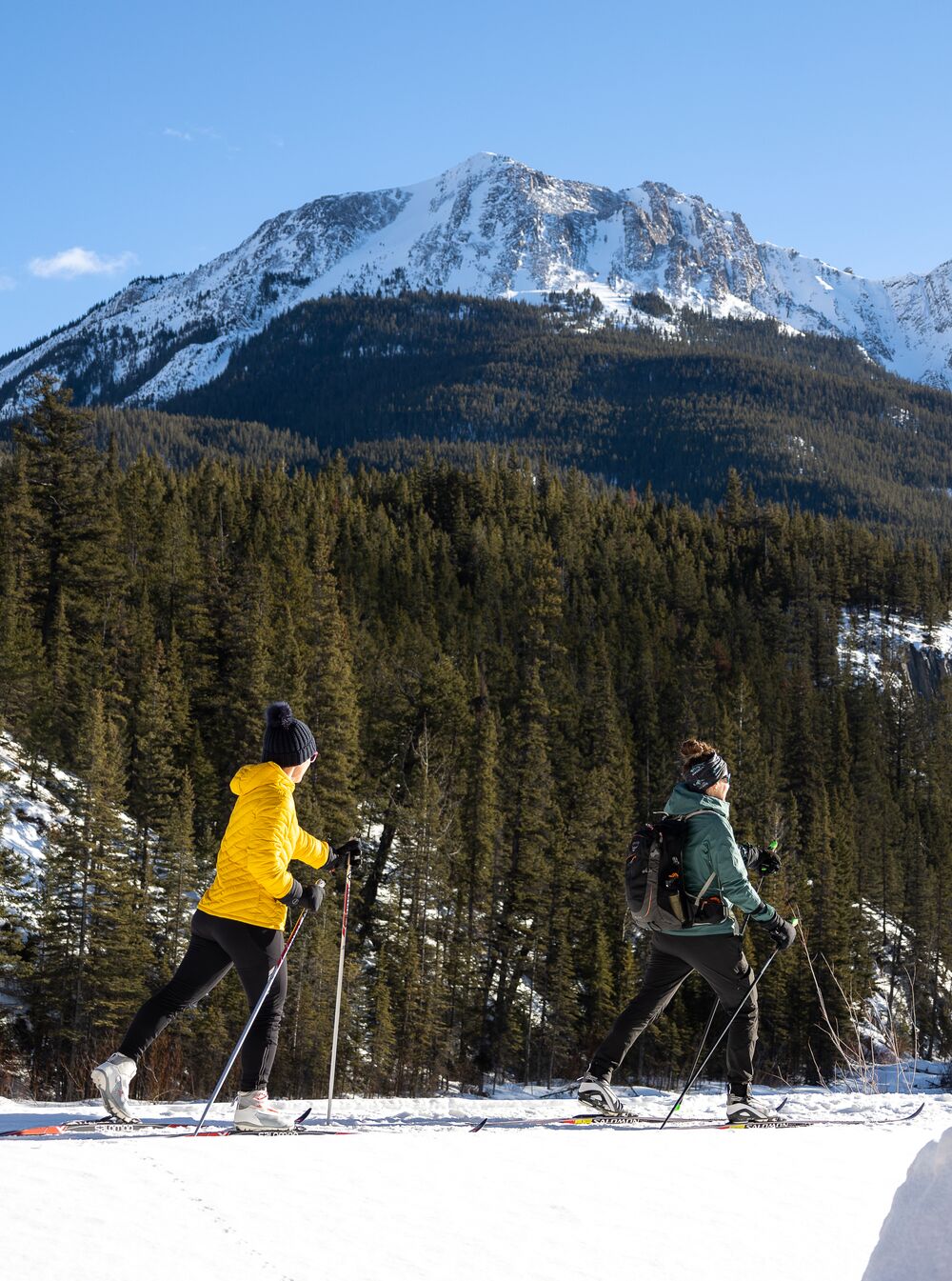 Two people cross country ski on a sunny day in Banff National Park.