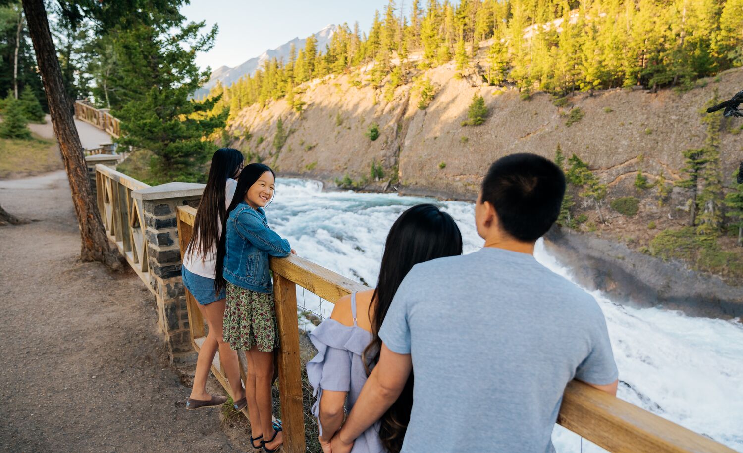 A family looks out over Bow Falls from the Bow River Pathway.