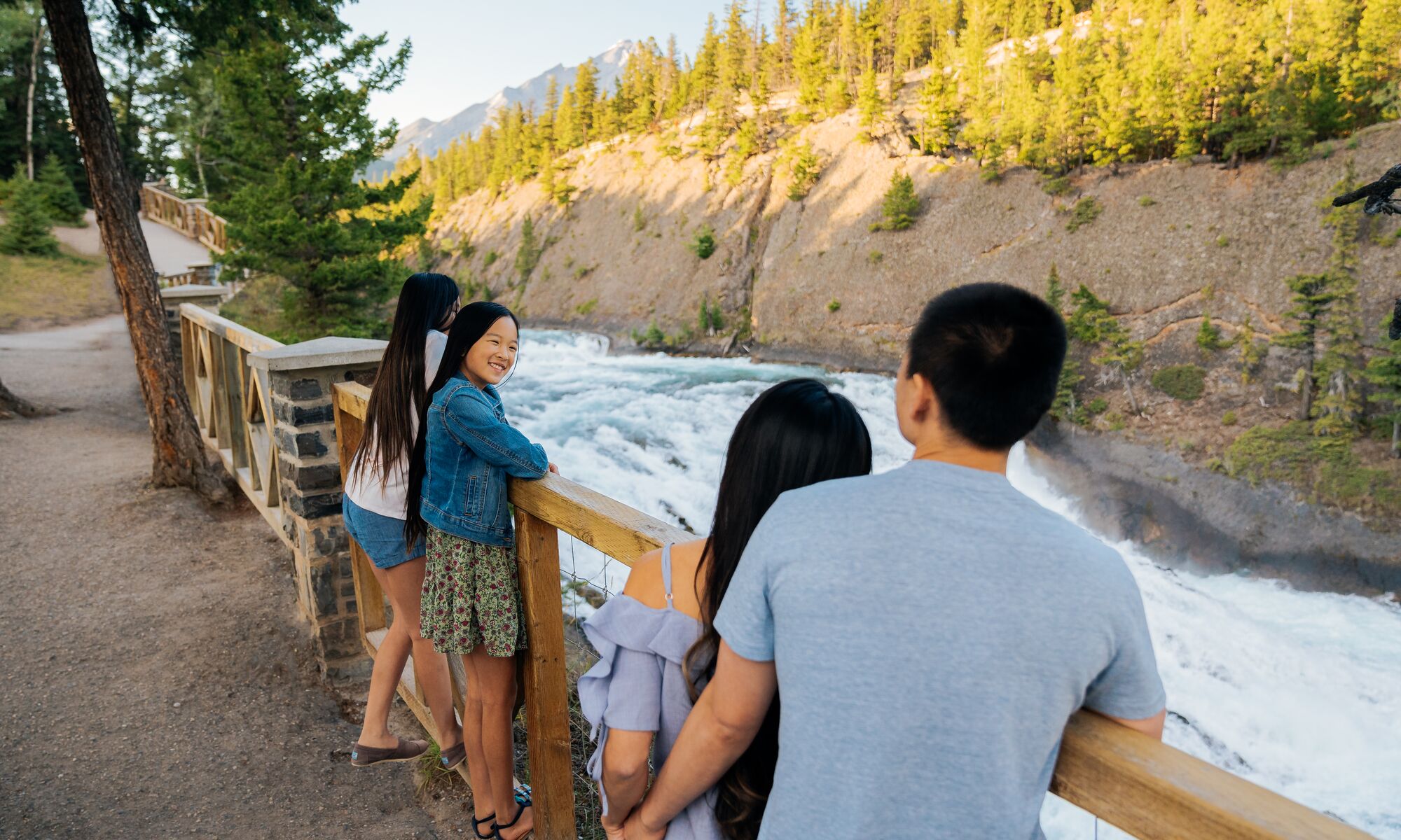 A family looks out over Bow Falls from the Bow River Pathway.