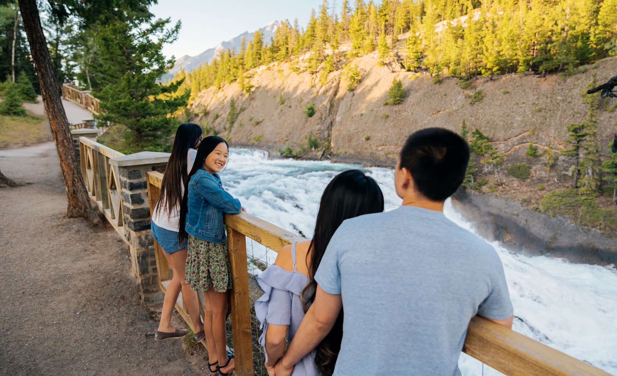 A family looks out over Bow Falls from the Bow River Pathway.