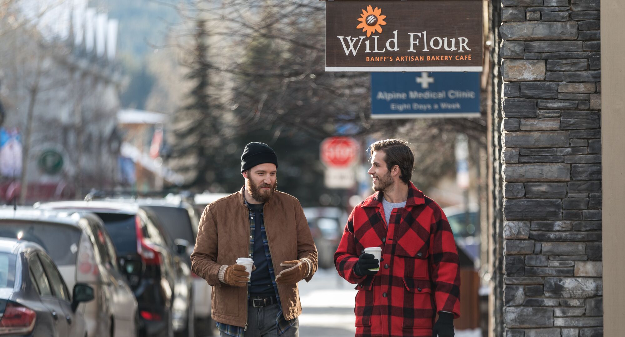 Two people walking down Bear Street with coffees in hand