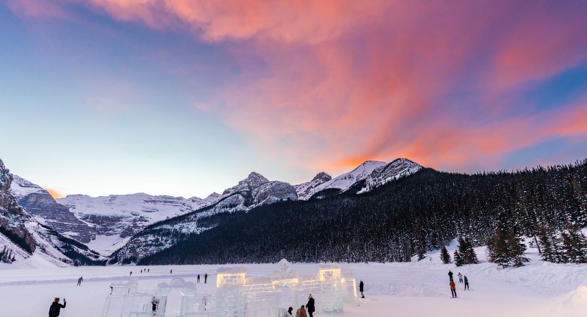 The skating rink and the ice castle underneath a red sunset at Lake Louise during Ice Magic in Banff National Park.