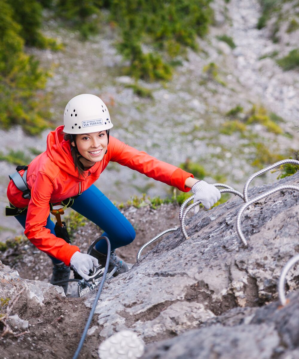 A person climbing a series of metal rungs at the Mt. Norquay Via Ferrata