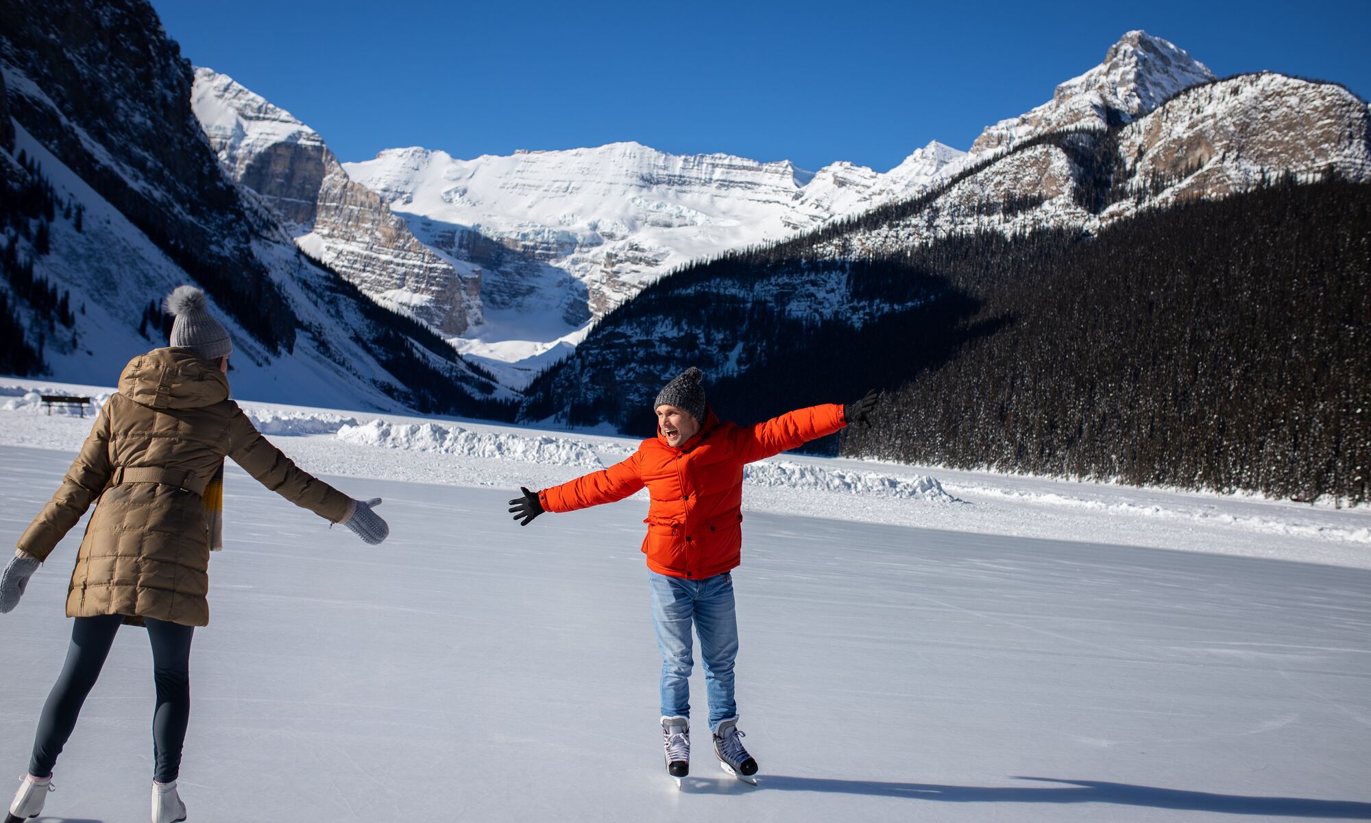 Two people skate on a frozen Lake Louise in Banff National Park in the winter.
