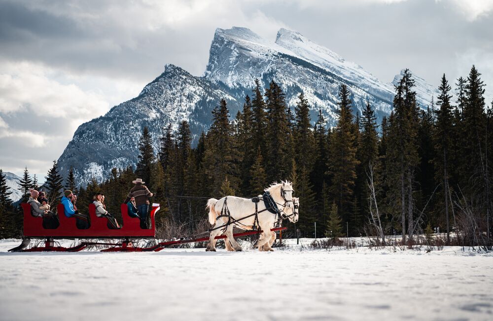 Group of people enjoying a sleigh ride through Banff with views of Mount Rundle
