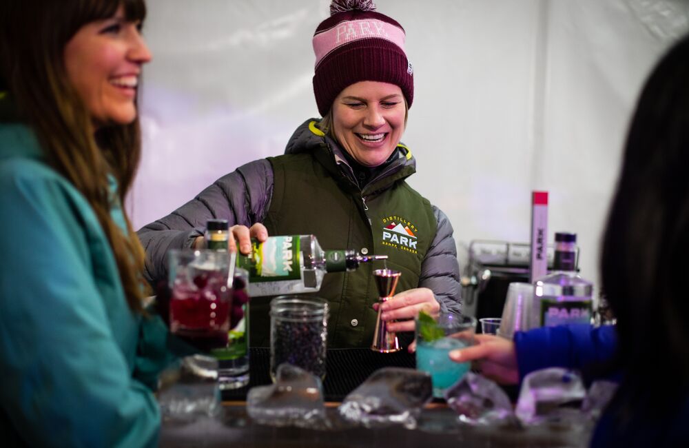 A woman pours a cocktail on Bear Street during an outdoor cocktail festival.