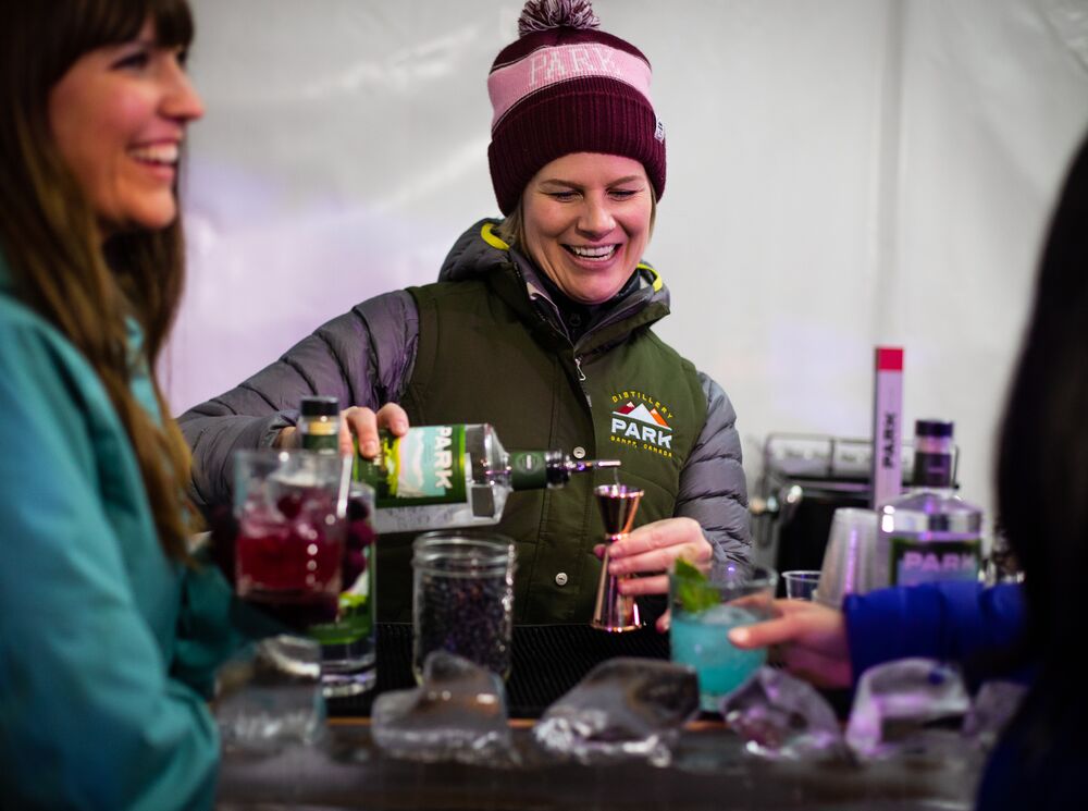 A woman pours a cocktail on Bear Street during an outdoor cocktail festival.