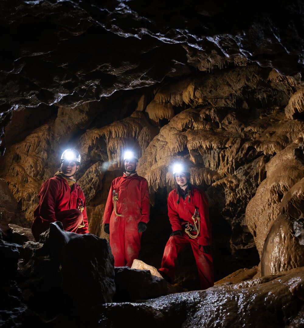 Group of people with head torches on deep in a cave on guided cave tour with Canmore Cave Tours