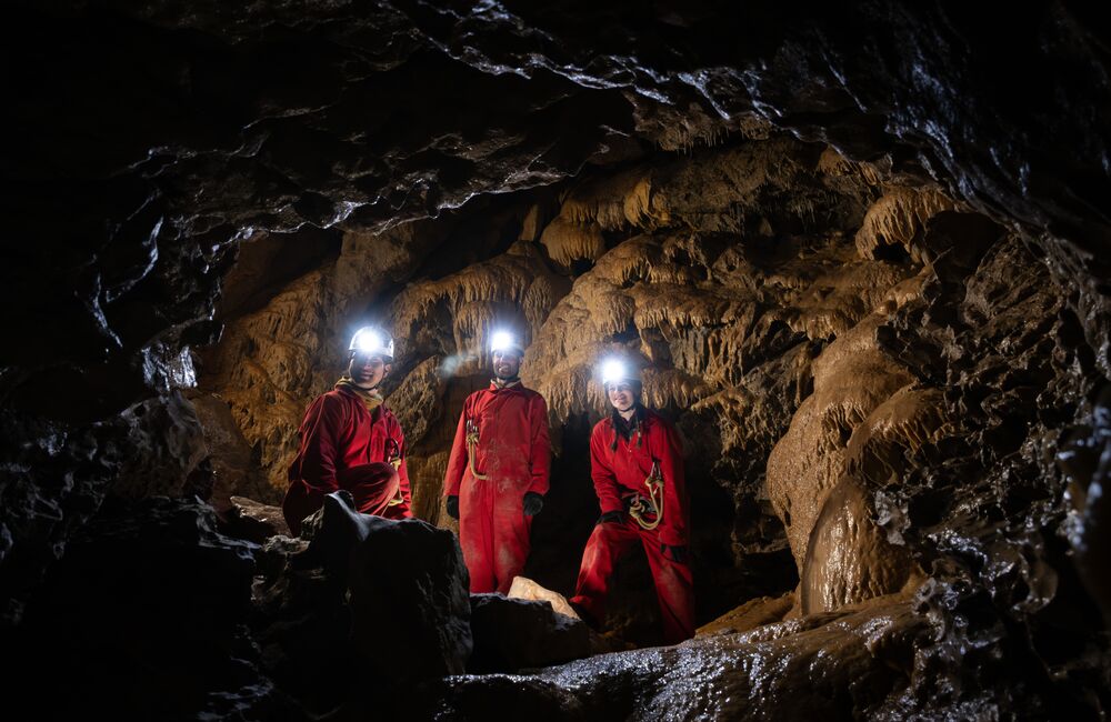 Group of people with head torches on deep in a cave on guided cave tour with Canmore Cave Tours