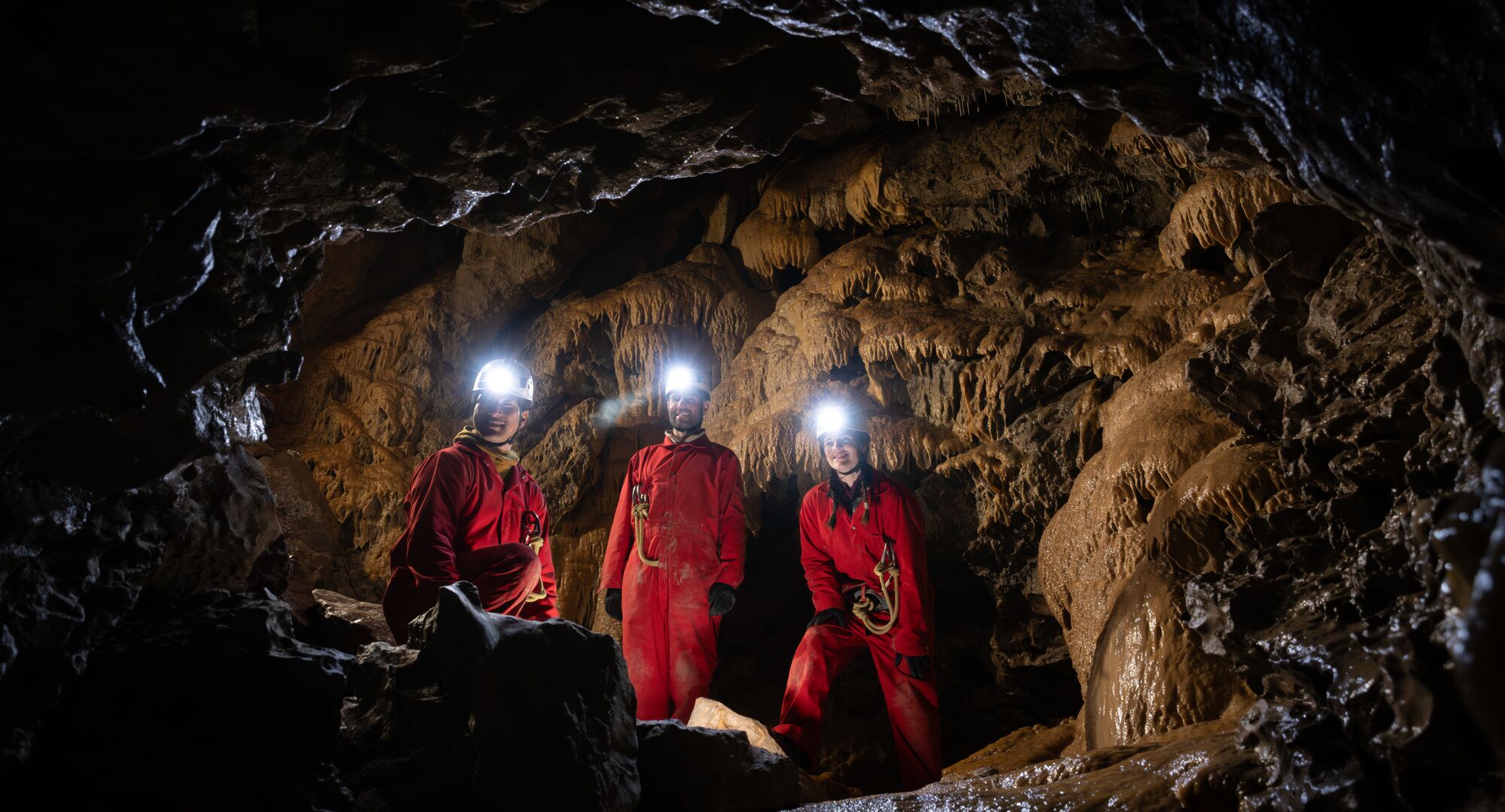 Group of people with head torches on deep in a cave on guided cave tour with Canmore Cave Tours