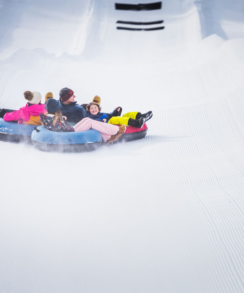 Family having fun tubing down a snowy slope at the Lake Louise Ski Resort