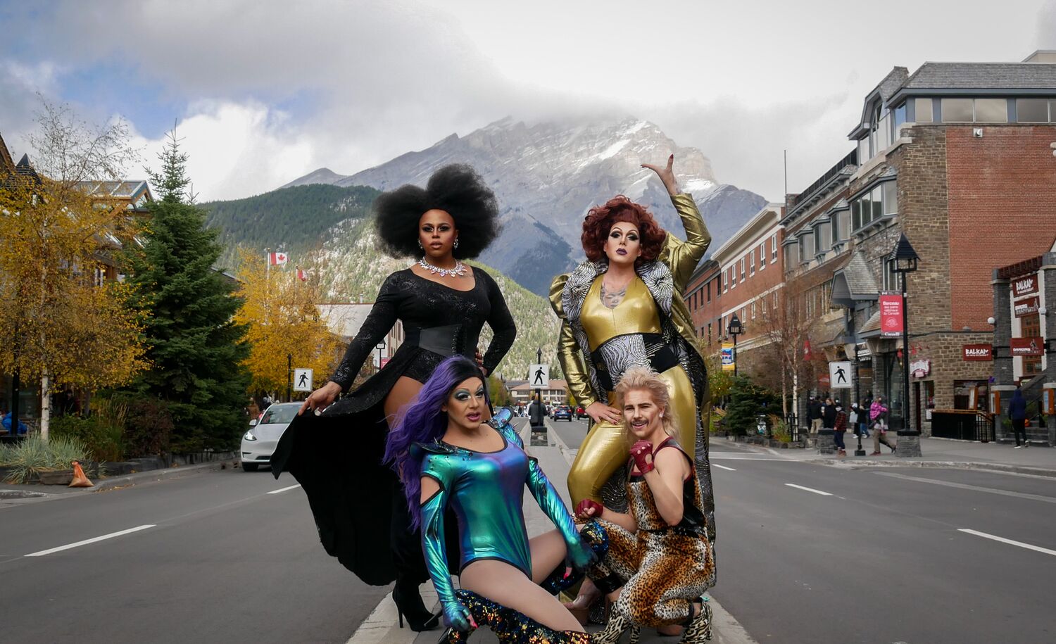 Four drag performers pose on Banff Ave with Cascade Mountain in the background