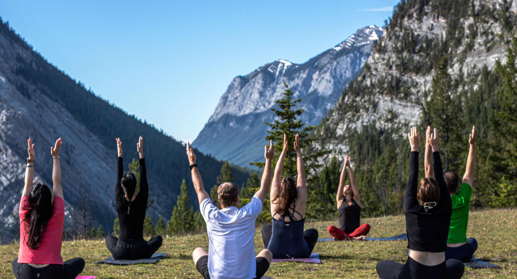 Mixed group doing outdoor yoga with mountains in background