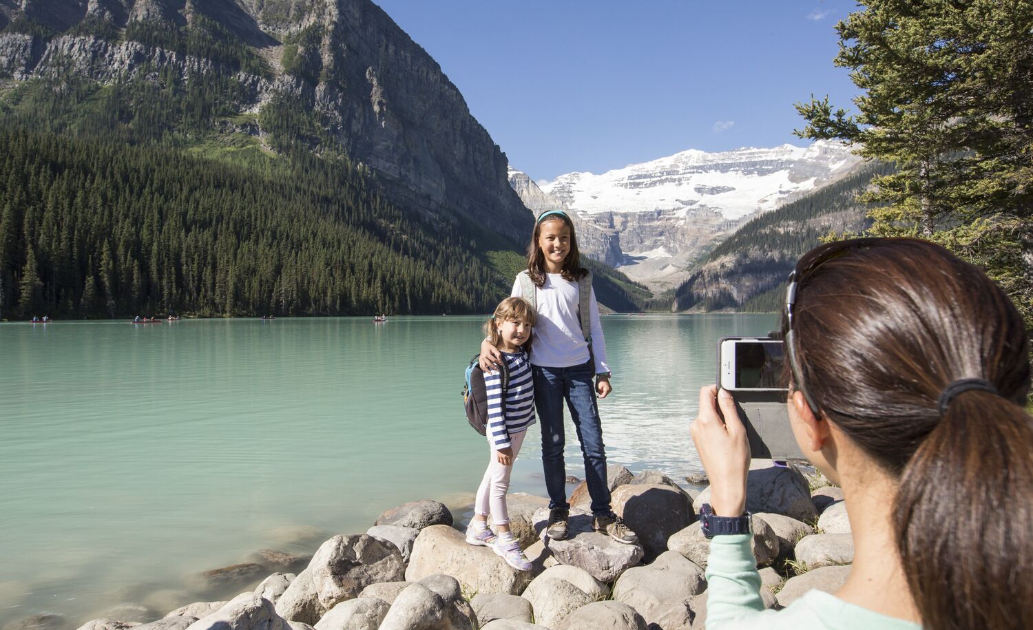 Two kids pose for a photo on the Lake Louise lakeshore trail in Banff National Park.