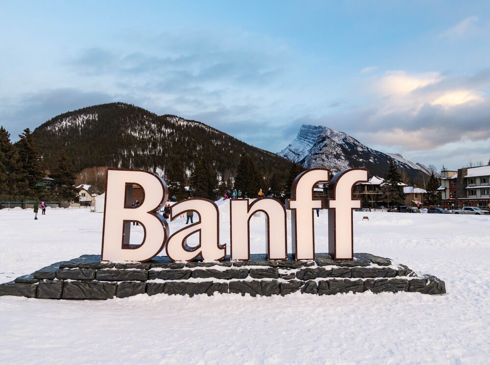 The illuminated Banff sign with Sulphur Mountain and Mount Rundle in the Banff townsite of Banff National Park.
