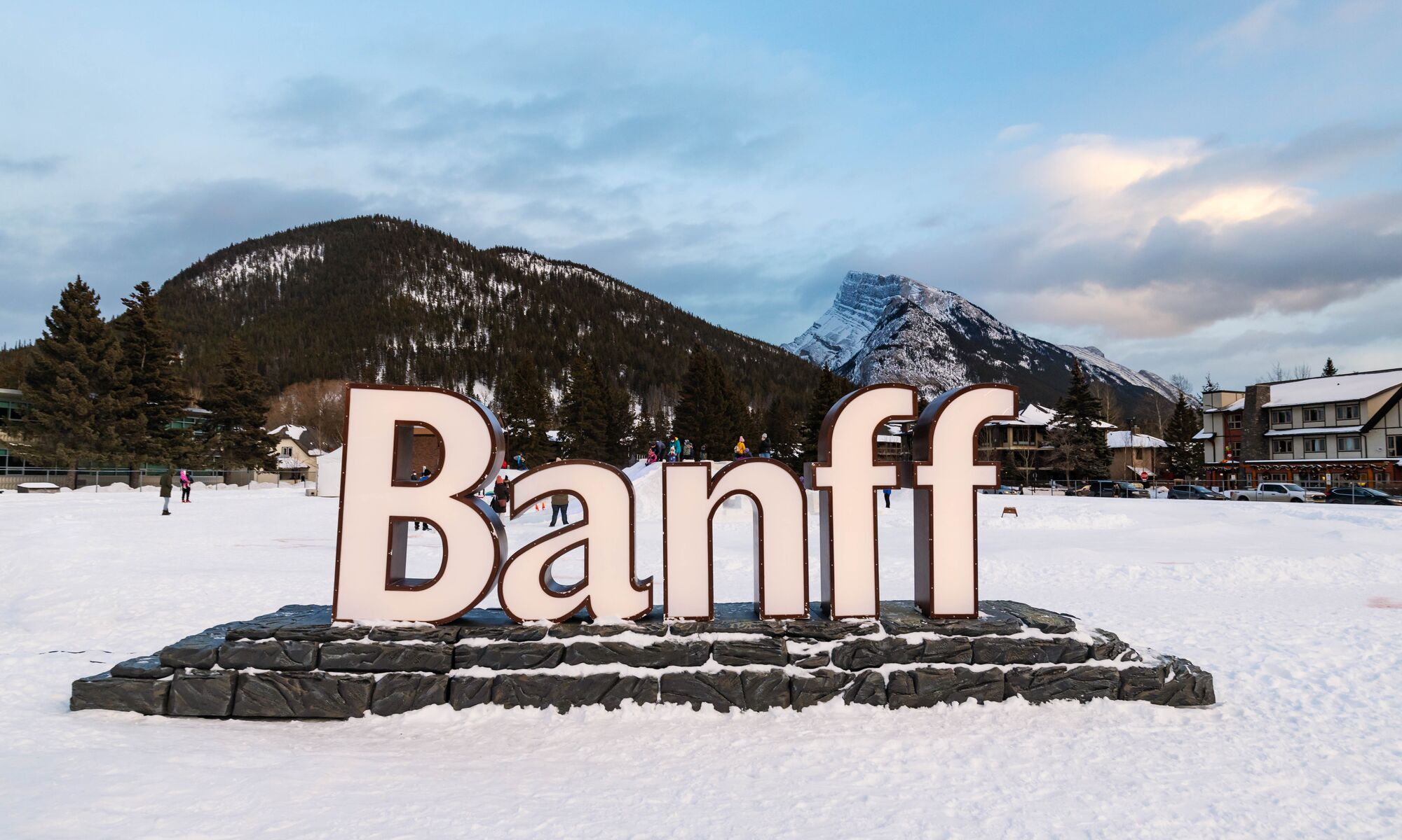 The illuminated Banff sign with Sulphur Mountain and Mount Rundle in the Banff townsite of Banff National Park.