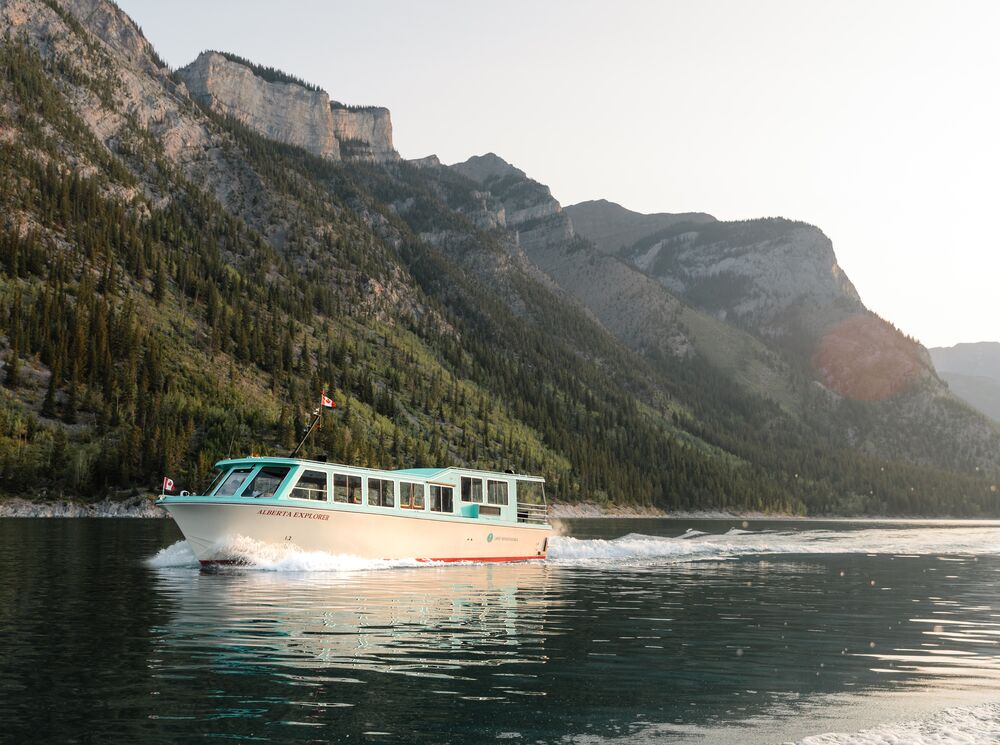 The Lake Minnewanka Cruise out on Lake Minnewanka in Banff National Park with a mountain in the background.