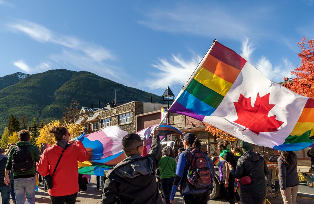 Banff Pride Parade walking down Banff Avenue with a view of Cascade Mountain in the background.