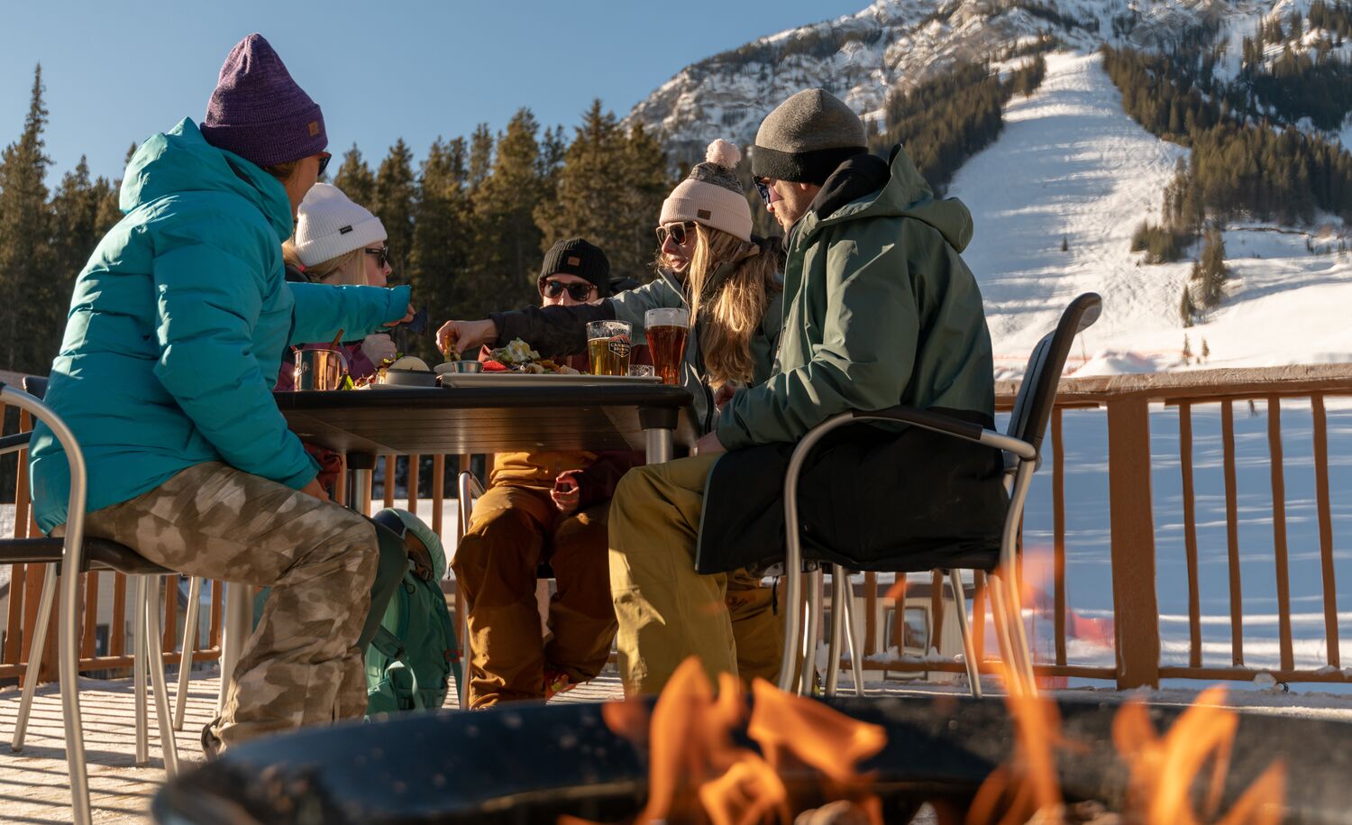 A group of friends enjoys food and drinks on a patio at Mt. Norquay ski resort in Banff National Park. 