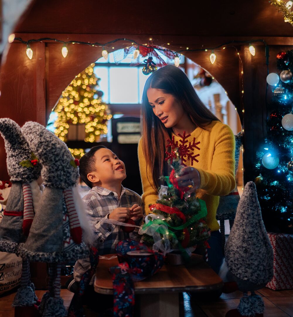 A mom and son look at each other in a giant gingerbread house at Christmas in Banff at the Rimrock Resort.