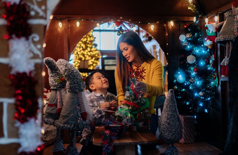 A mom and son look at each other in a giant gingerbread house at Christmas in Banff at the Rimrock Resort.
