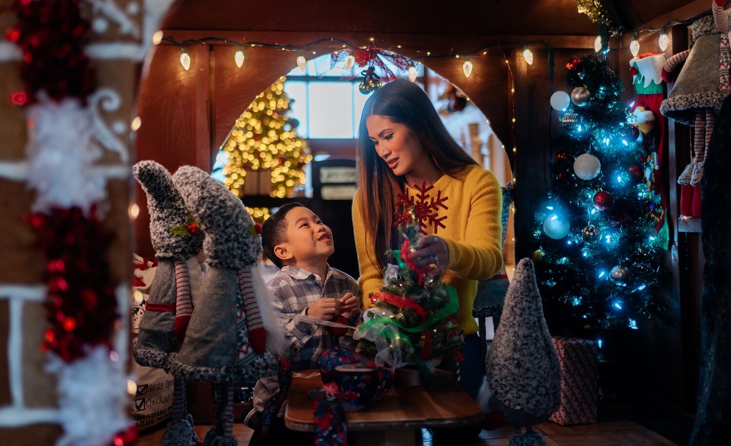 A mom and son look at each other in a giant gingerbread house at Christmas in Banff at the Rimrock Resort.