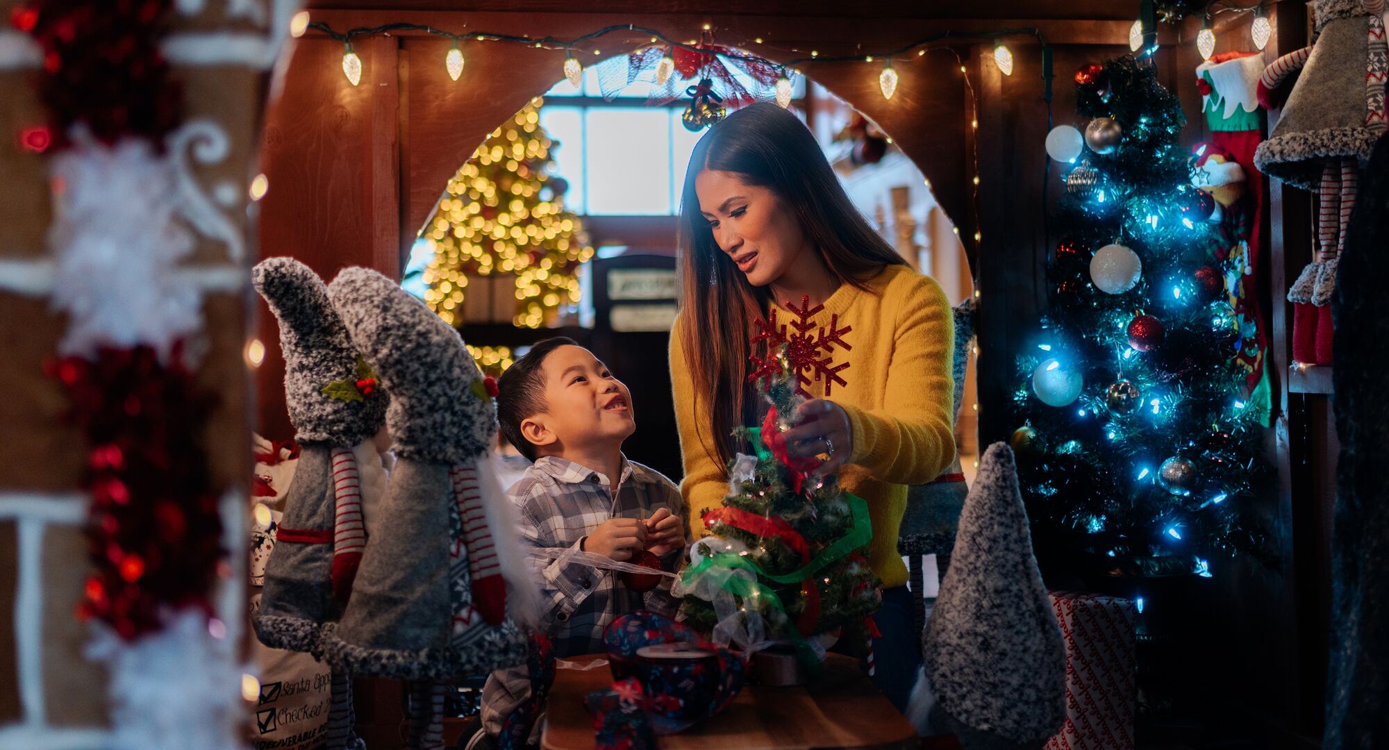A mom and son look at each other in a giant gingerbread house at Christmas in Banff at the Rimrock Resort.