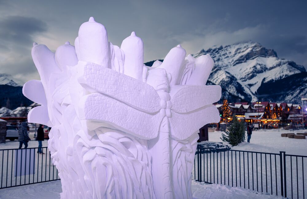 A snow sculpture at blue hour during SnowDays with Cascade Mountain in the background in Banff National Park.
