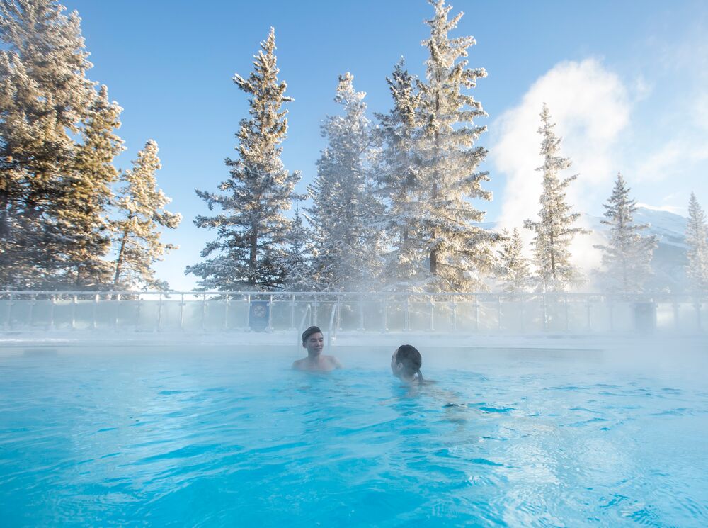 Two people enjoying a soak in the Banff Upper Hot Springs on a cool morning