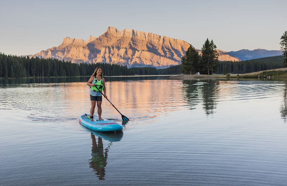 Person stand up paddleboarding on Two Jack Lake at sunrise