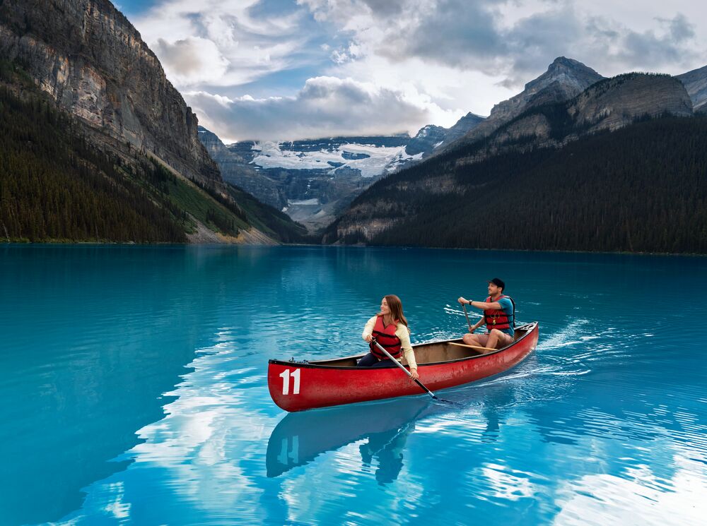Two people canoe on Lake Louise in a red canoe.