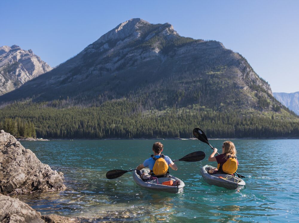 Two people kayak on Lake Minnewanka in Banff National Park.