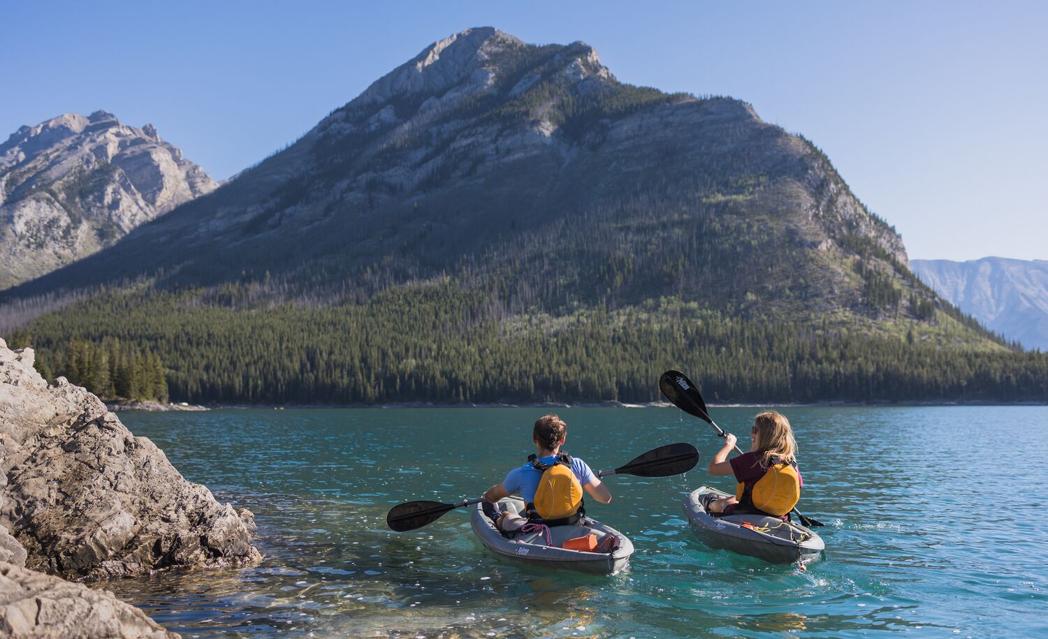Two people kayak on Lake Minnewanka in Banff National Park.