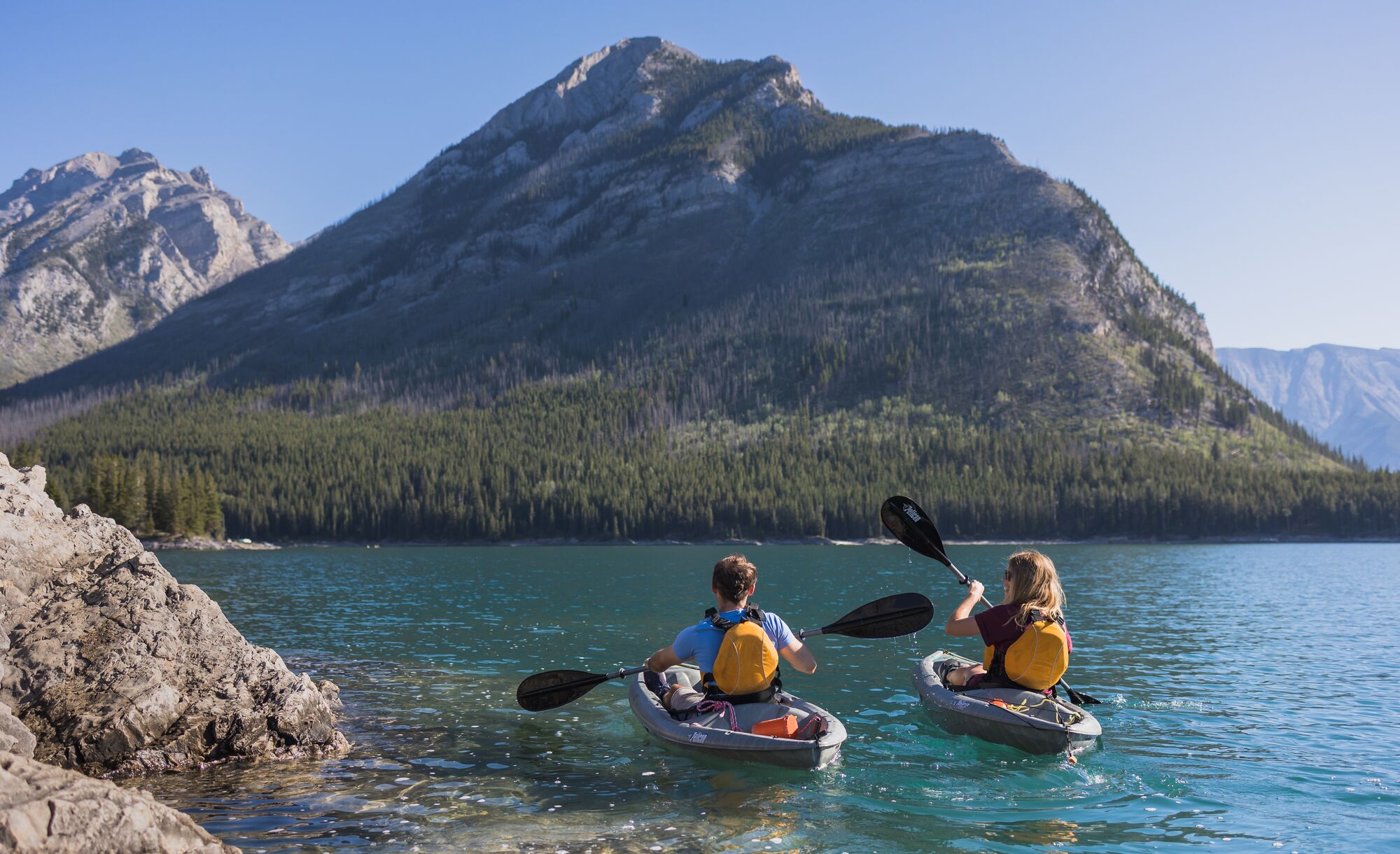 Two people kayak on Lake Minnewanka in Banff National Park.