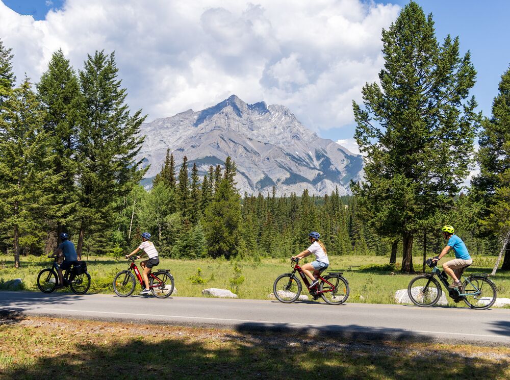 Four people biking along the golf course road, one of the most popular things to do in Banff National Park in June
