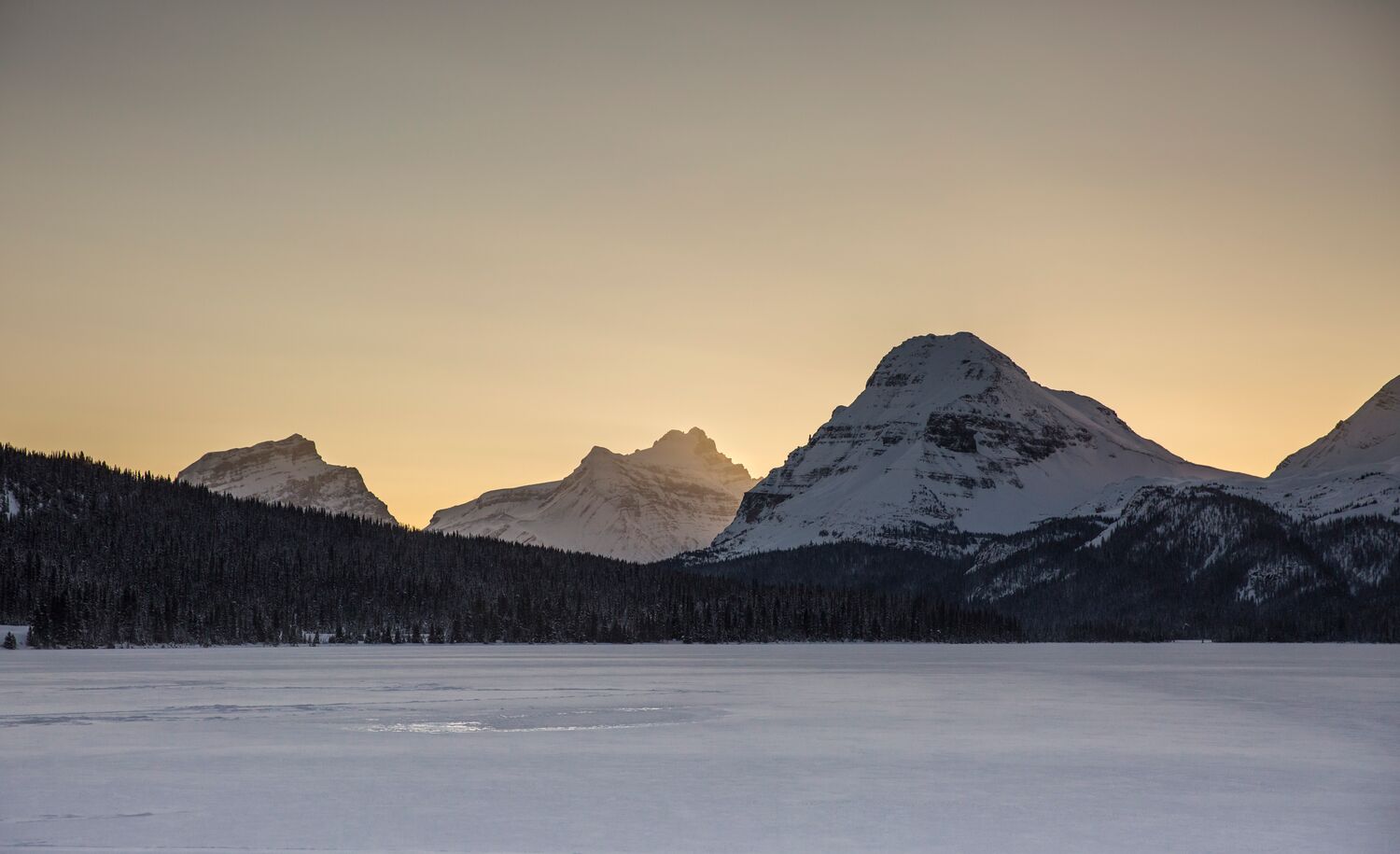 Bow Lake at sunset in the winter, looking towards three big mountains.