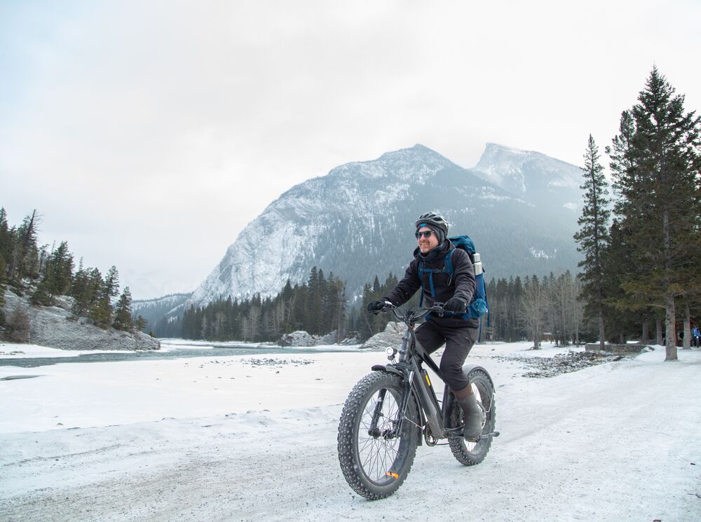 A person fat bikes on a trail near Bow Falls in the winter in Banff National Park