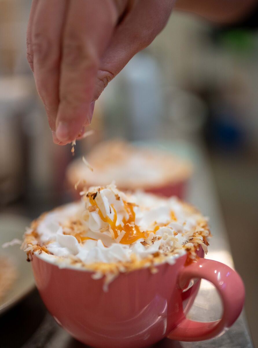 A person sprinkles coconut onto a hot chocolate at Mountain Folk in Banff.