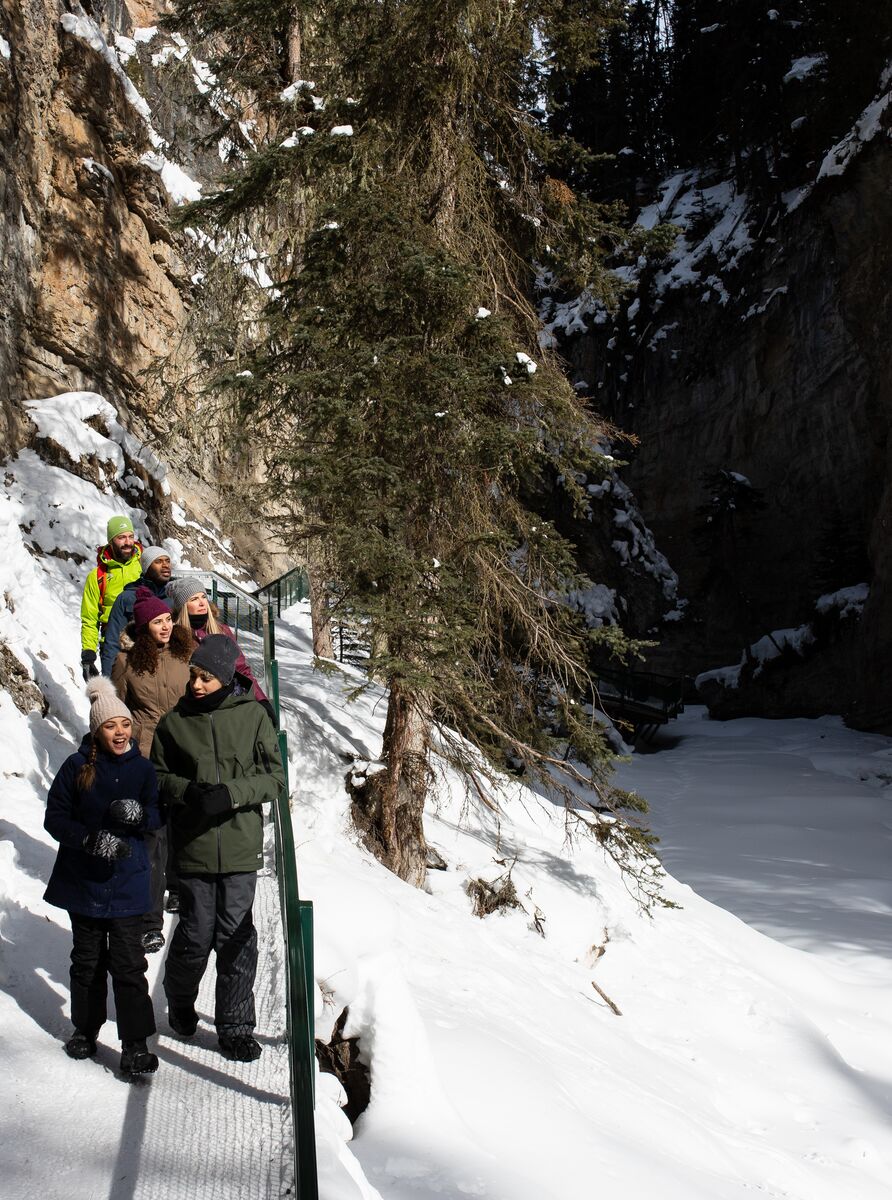 A family walks on a boardwalk in Johnston canyon in the winter in Banff National Park.
