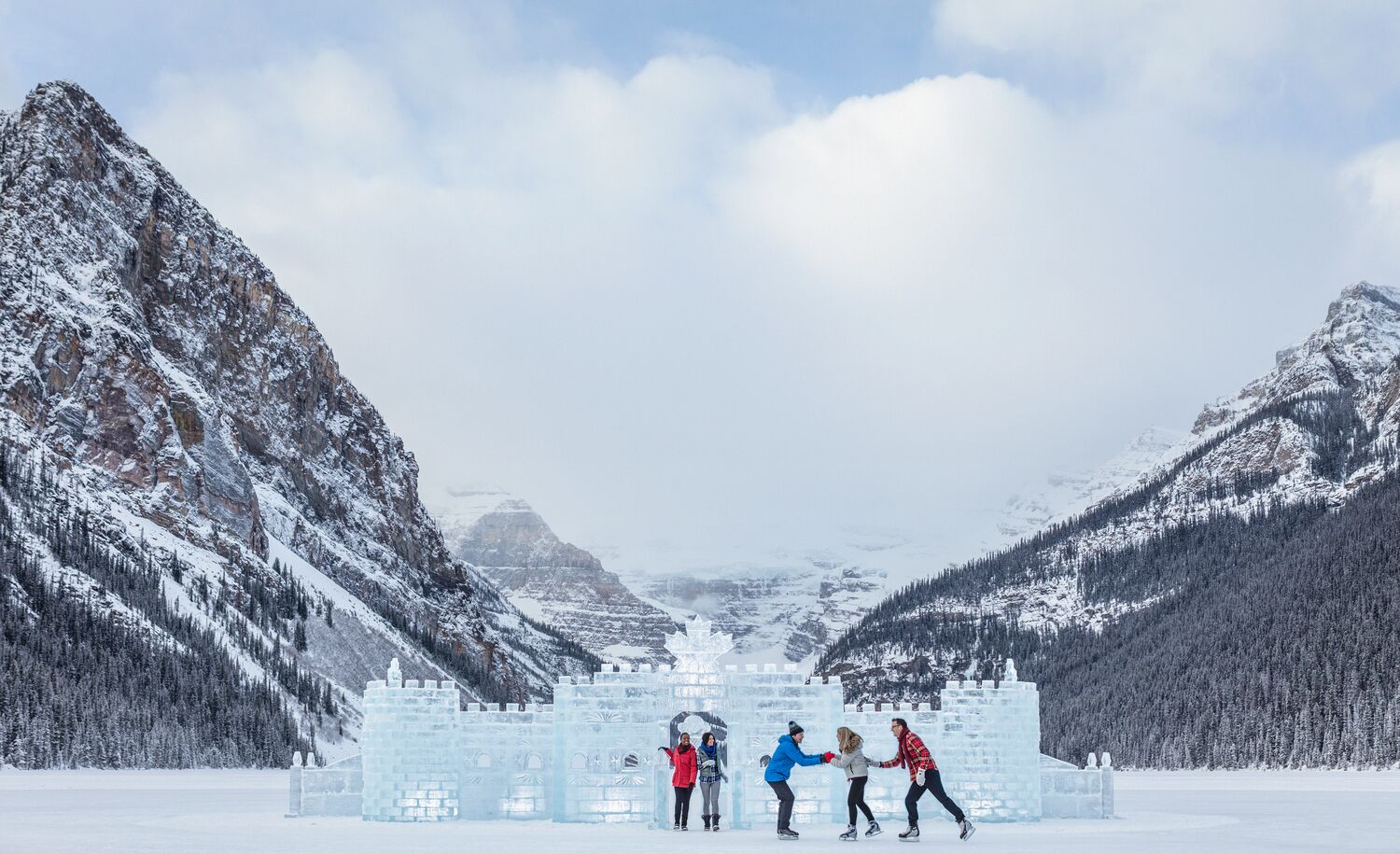 A group of friends skating on Lake Louise in the winter with the ice castle behind them