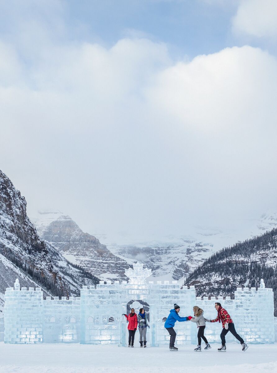 A group of friends skating on Lake Louise in the winter with the ice castle behind them