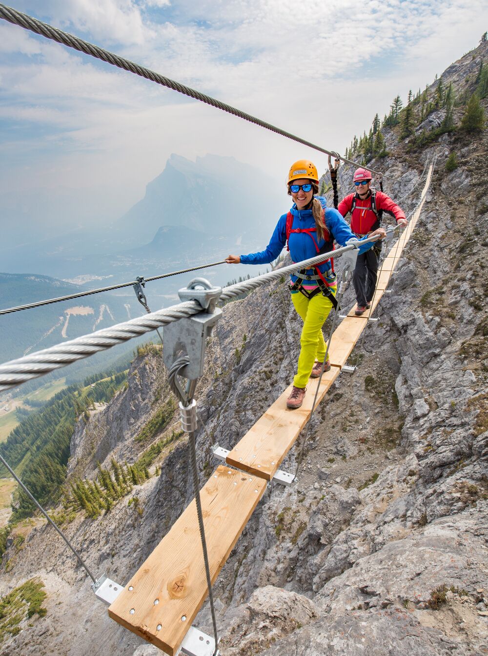 Two people on a small bridge suspended on the Mt. Norquay via feratta in Banff National Park..
