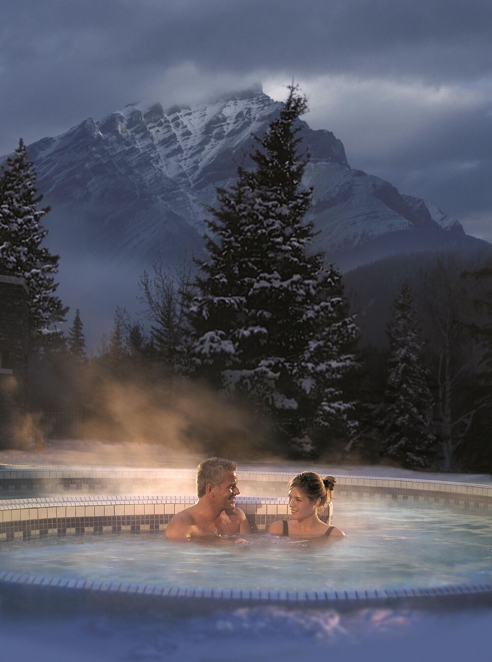 Two people soak in the outdoor hot tub at the Willow Stream Spa at the Fairmont Banff Springs in Banff National PArk.