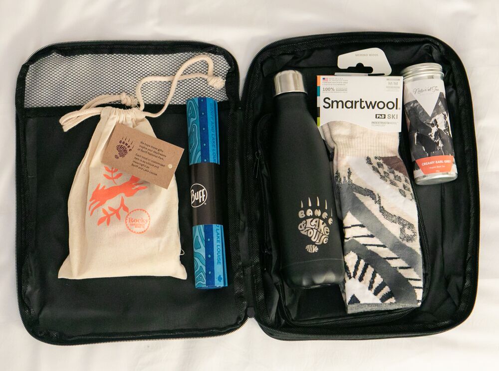 Suitcase with souvenirs from Banff: Water bottle, Smartwool socks, Rocky Mountain Soap, a Buff, and local tea.