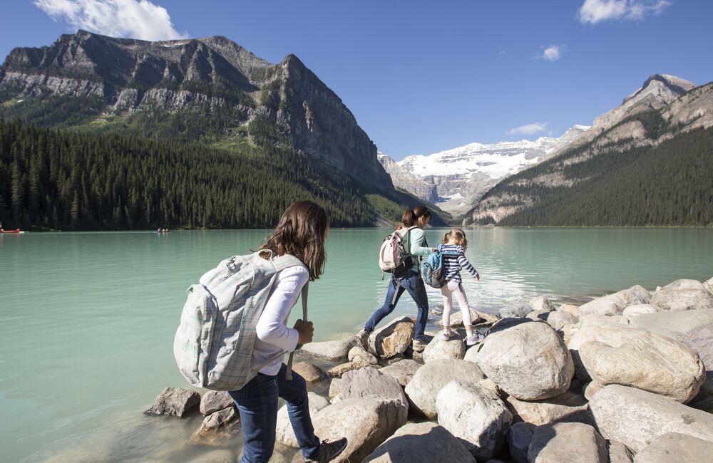A family hiking along the shoreline of Lake Louise in the summer