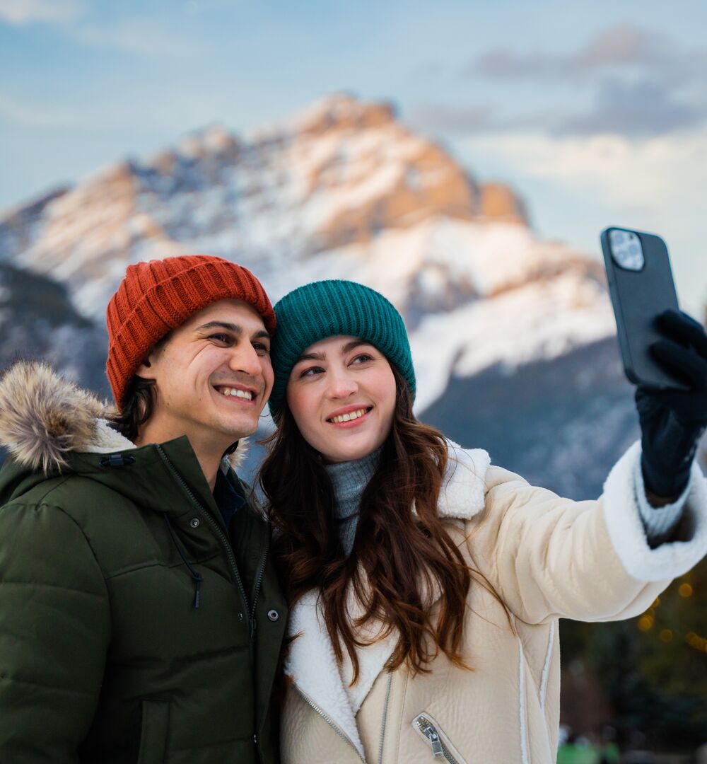 A couple takes a selfie together with Cascade Mountain in the background.