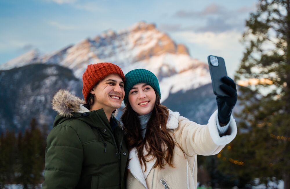 A couple takes a selfie together with Cascade Mountain in the background. 