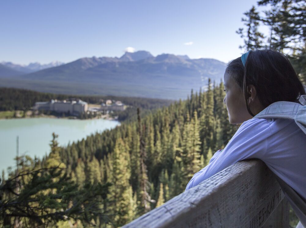 A girl standing at Fairview Lookout looking at the view over Lake Louise in the summer