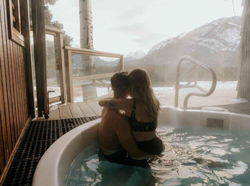 A couple in a hot tub in winter at the Juniper Hotel in Banff.